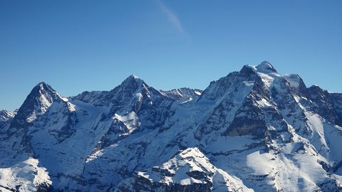 Scenic view of snowcapped mountains against clear blue sky