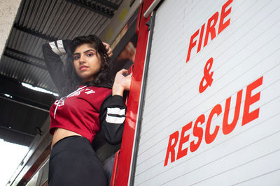 Portrait of young woman standing against red flag