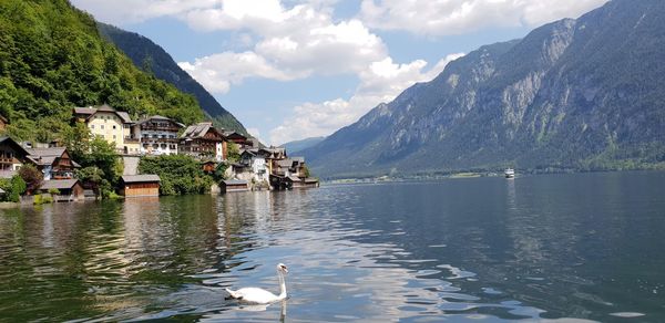 Houses by lake and mountains against sky