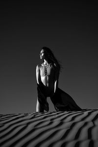 Woman looking away while standing on sand