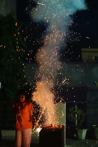 Girl standing by firework display at night