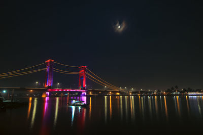 Illuminated bridge over river at night