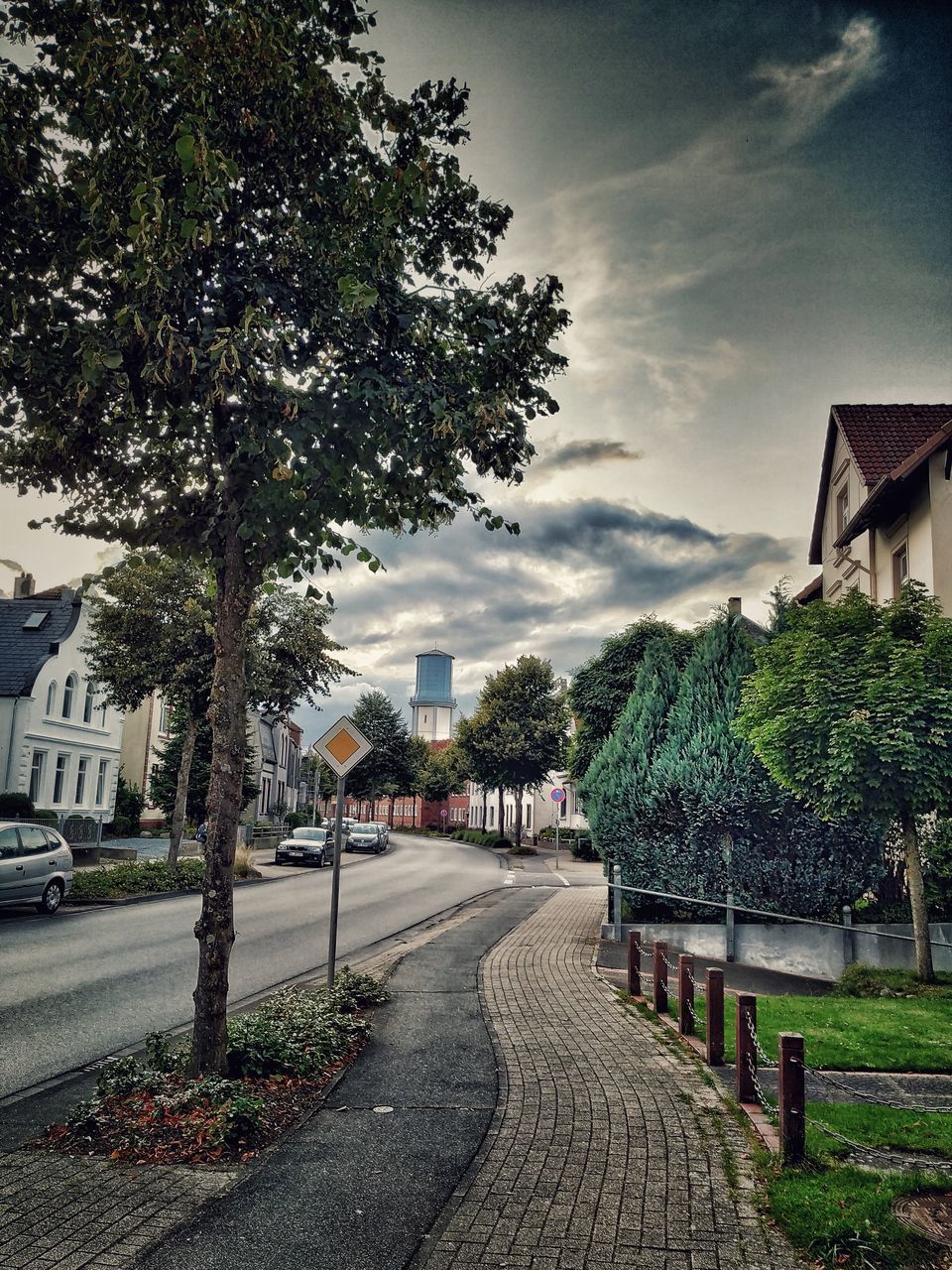 FOOTPATH AMIDST TREES AND BUILDINGS AGAINST SKY