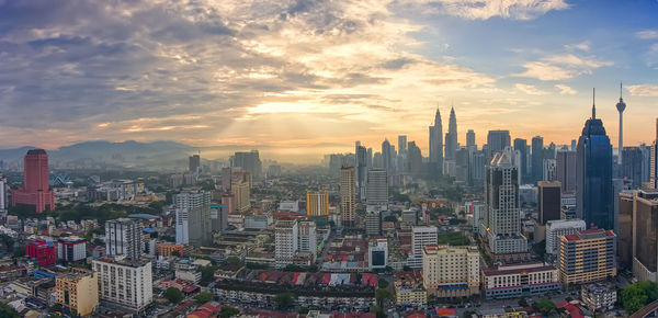 Aerial view of cityscape against cloudy sky