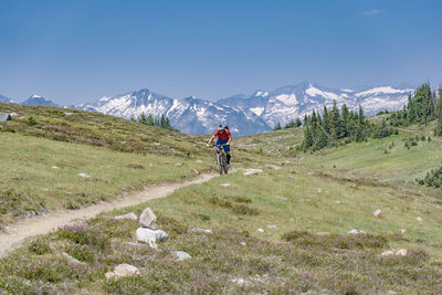 Man riding bicycle on mountain against sky