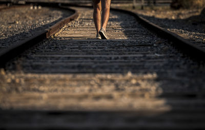 Low section of person standing on railroad track during sunset