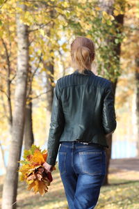 Rear view of woman standing amidst trees during autumn