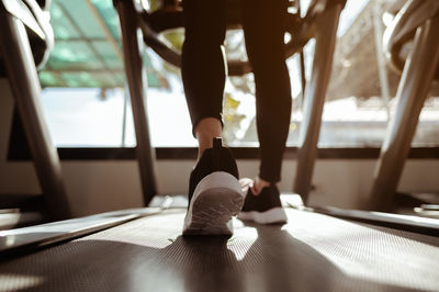 Low section of woman walking on treadmill at gym