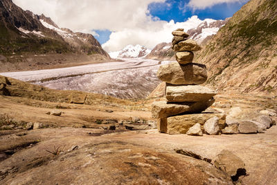 View of rock pile at a glacier against cloudy sky