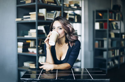 Portrait of young woman drinking coffee indoors