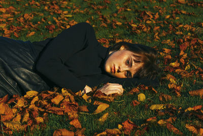 Portrait of young woman lying down on field during autumn