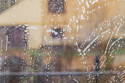 The window is covered in soap suds. the concept of cleaning and washing home windows. close-up
