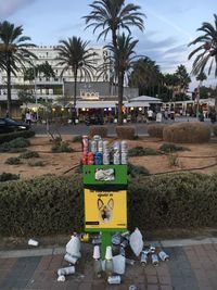 Garbage bin by street in city against sky