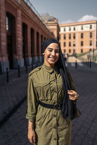 Portrait of young woman standing in city