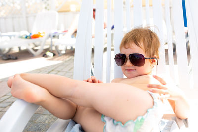 Small child in panama hat plays in the summer on sunny day near swimming pool