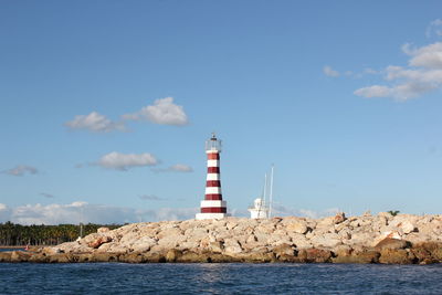 Lighthouse by sea against sky