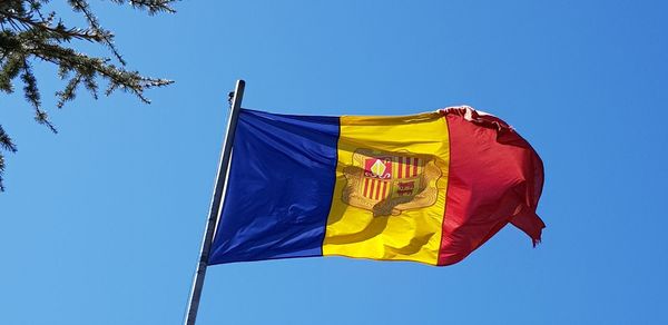 Low angle view of flags flag against clear blue sky