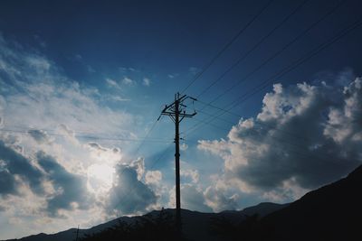 Low angle view of silhouette electricity pylon against sky