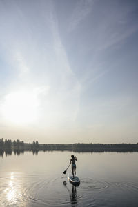 Woman doing standup paddleboarding in lake