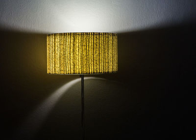 Close-up of illuminated lamp against wall at home