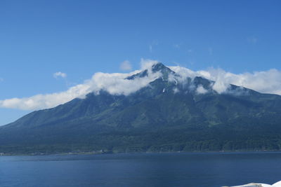 Scenic view of sea and mountains against blue sky