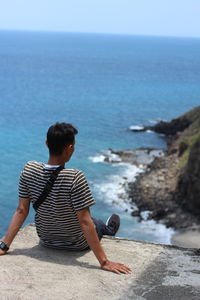 Rear view of man looking at sea against sky