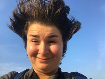 Close-up portrait of woman smiling against blue sky