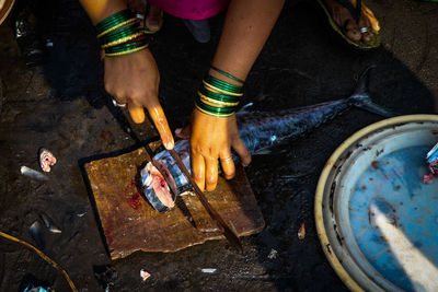 Cropped hands of woman cutting fish at home