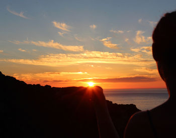 Silhouette of people on sea at sunset