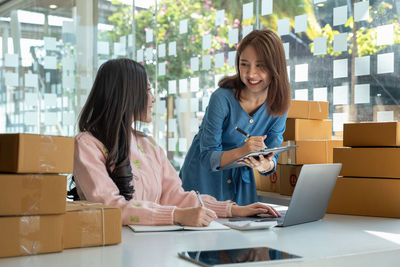 Happy businesswoman with colleague working at desk