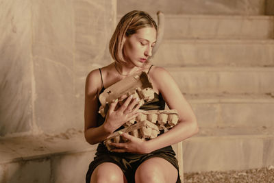 Portrait of young woman sitting on wall