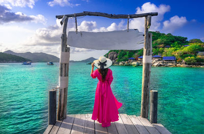 Rear view of woman standing by sea against sky