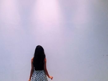 Rear view of woman standing against white wall