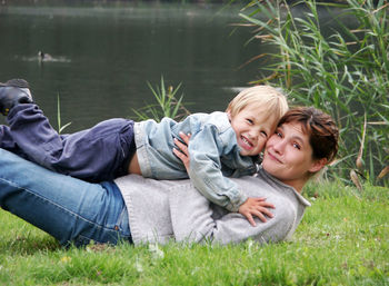 Portrait of smiling woman playing with son on grass