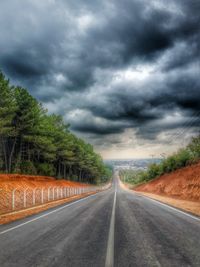 Empty road with trees in background