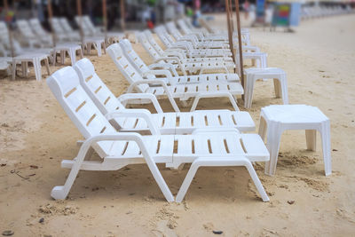 Empty chairs and tables on sand at beach