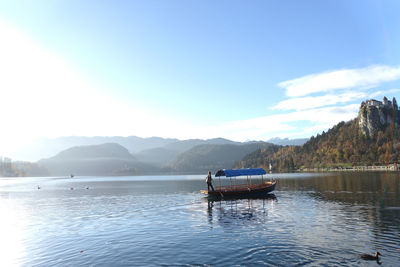 Man sailing boat in lake bled against sky