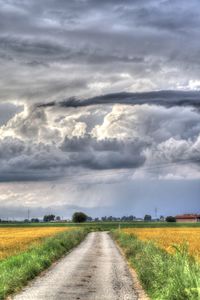 Road amidst agricultural field against sky