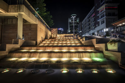 Illuminated buildings by street in city at night