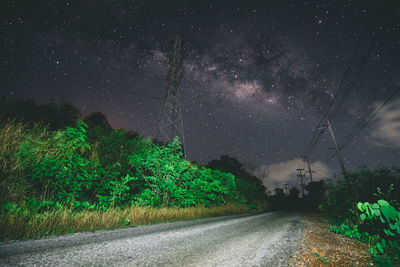 Road amidst trees against sky at night
