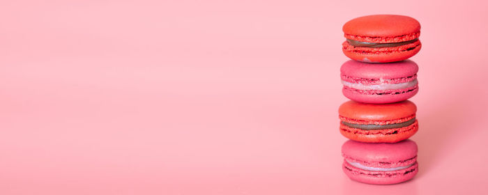 Close-up of multi colored candies on table against pink background