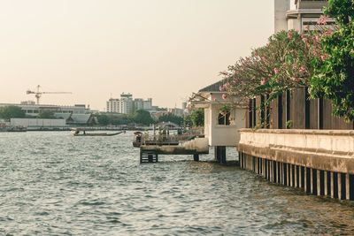 Buildings by river against clear sky