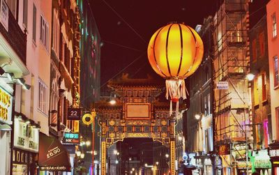 Low angle view of illuminated lantern amidst buildings in chinatown at night
