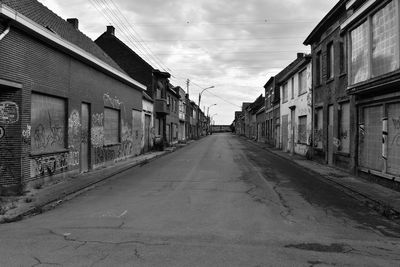 Empty road amidst buildings against sky