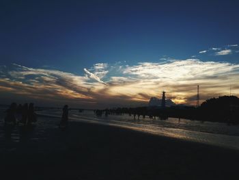 Silhouette of beach against cloudy sky