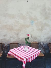 Flower vase on table at sidewalk cafe against wall