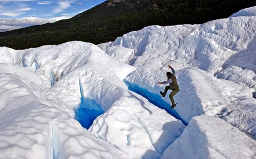 High angle view of man jumping on glacier