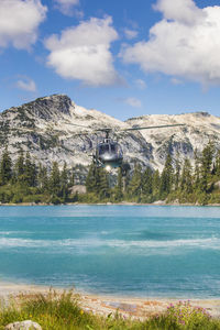 Helicopter flying low in mountains over alpine lake.