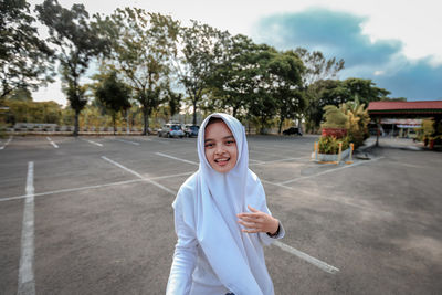 Portrait of smiling woman wearing hijab standing on road