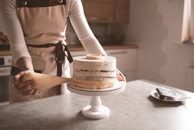 Woman making tasty cake with cream cheese on kitchen table closeup. cooking at home. homemade.